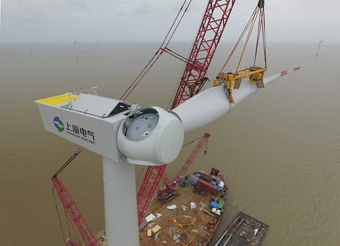 Services Aerial view of a wind turbine being installed over the sea, showcasing renewable energy construction.